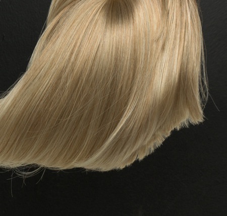 Dense, straight blond wig lying on dark backgroundの写真素材