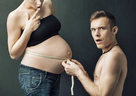 Glad parents measuring on pregnant woman's bellyの写真素材