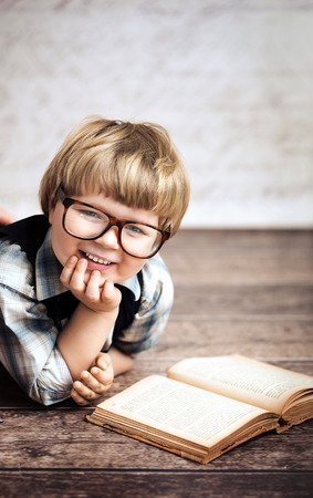 Cheerful smiling little boy reading a bookの写真素材