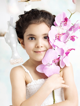 Little brunette girl holding a colorful flowerの写真素材