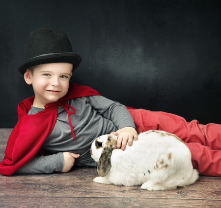 Little magician boy stroking a rabbitの写真素材