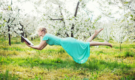 Adorable lady levitating during book readingの写真素材