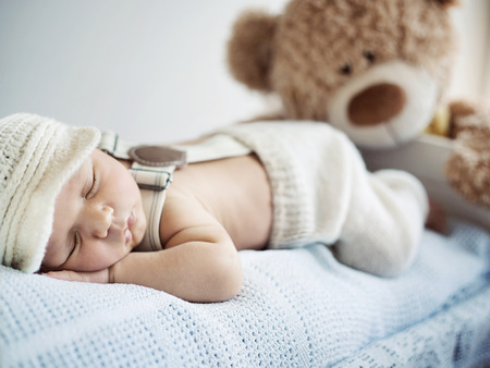 Newborn child sleeping with a teddy bearの写真素材