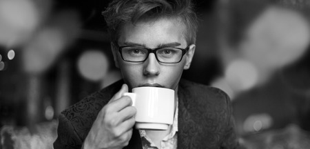 Handsome young guy drinking aromatic black coffeeの写真素材