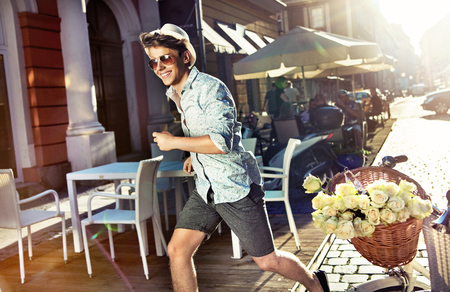 Smiling man running next to the basket full of rosesの写真素材