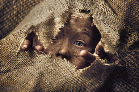 Little homeless child wearing a bagの写真素材