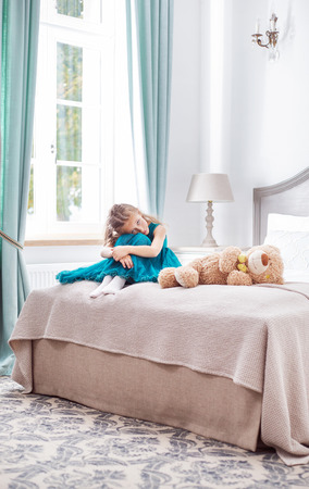 Portrait of the little sad girl alone in the bedroomの写真素材