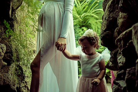 Pregnant mother walking with her little, cute daughterの写真素材