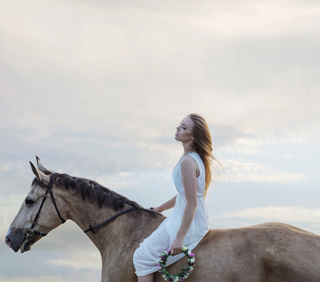 Sensual blond lady riding a brown stallionの写真素材