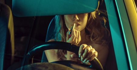 Attractive blonde lady using lipstick in a carの写真素材