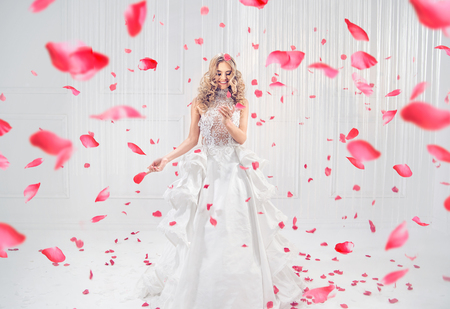 Pretty, elegant blonde dancing among red rose petalsの写真素材