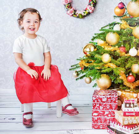 Cute little child sitting nesxt to the Christmas treeの写真素材