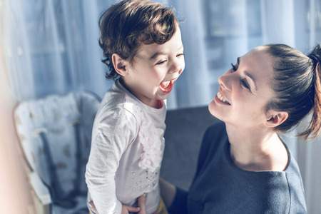 Relaxed mother cuddling her beloved daughterの写真素材