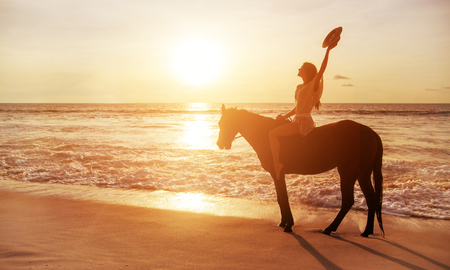 Brunette woman riding a horse alongside the coastlineの写真素材
