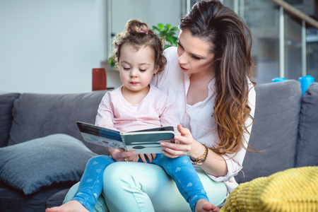 Young mother reading a book with her little daughterの写真素材