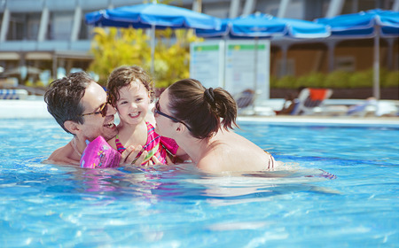 Cheerful family relaxing in the tropical swimming poolの写真素材