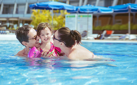 Cheerful family relaxing in the tropical swimming pool