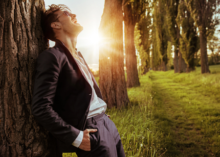 Calm, relaxed guy leaning on the treeの写真素材