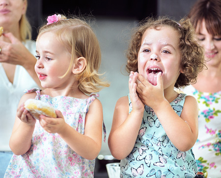 Two cute girls eating sweet, tasty doughnutsの写真素材