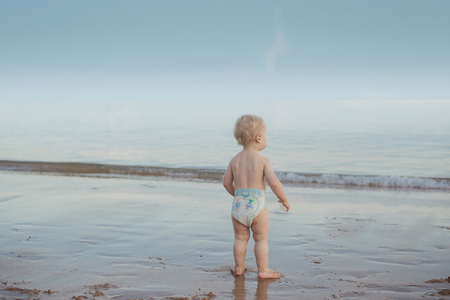 Cute, calm baby watching an ocean's waveの写真素材