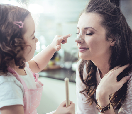 Cheerful mother and little daughter having fun in the kitchenの写真素材