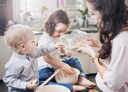 Mother baking a sweet cake with her childrenの写真素材