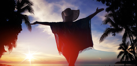 Relaxed lady looking at the sunset on tropical beachの写真素材
