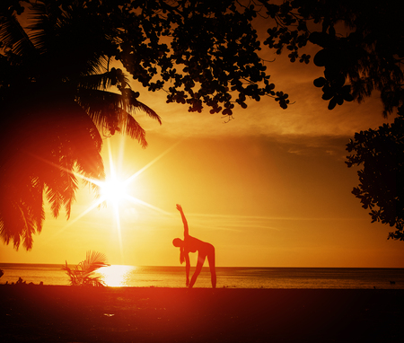 Flexible woman training on a tropical beachの写真素材
