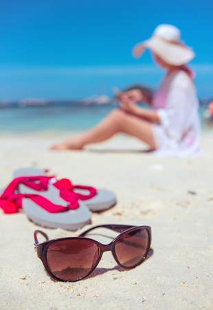 Relaxed woman using a smartphone on a tropical beachの写真素材