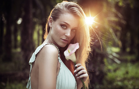 Portrait of a pretty, natural lady holding a tropical flowerの写真素材