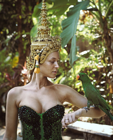Asian queen holding a green parrotの写真素材