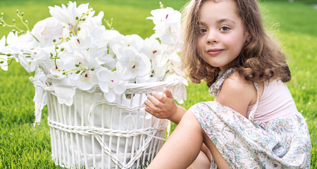 Portrait of a cute child holding a wicker basket with white plantsの写真素材