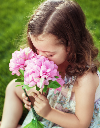 Pretty and cute child holding and sniffing flowersの写真素材
