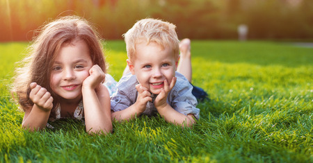Cheerful little  siblings relaxing on a fresh lawnの写真素材