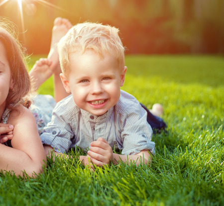 Cheerful little siblings relaxing on a fresh lawnの写真素材