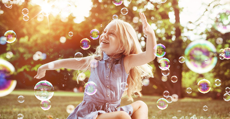 Little blond girl among lots of flying soap bubblesの写真素材