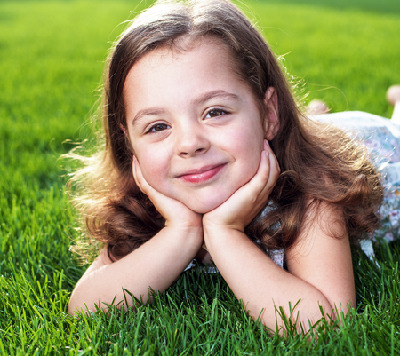 Closeup portrait of a cute little child lying on a fresh lawnの写真素材