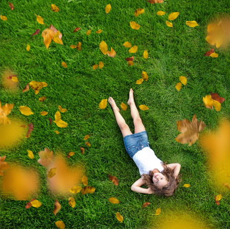 Relaxed little girl lying on a fresh, green meadowの写真素材