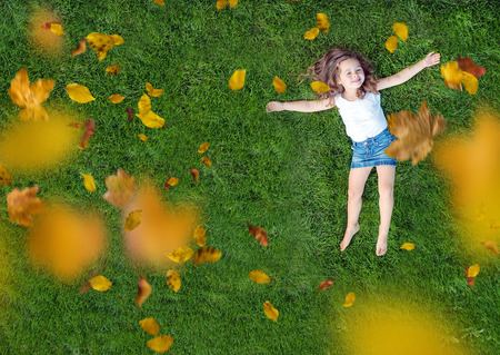 Relaxed little girl lying on a fresh, green meadowの写真素材