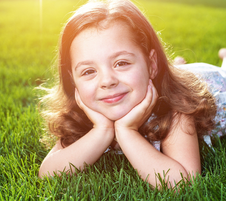 Closeup portrait of a cute little child lying on a fresh lawnの写真素材