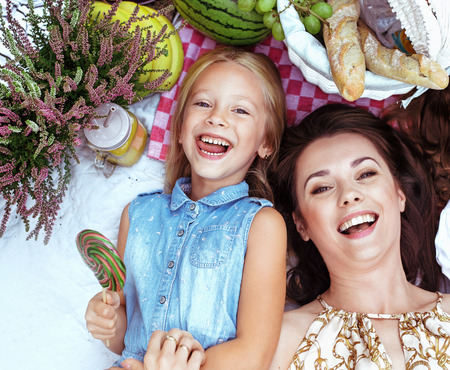 Mother and daughter lying on a picnic blanket among refreshmentsの写真素材