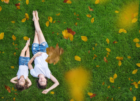 Conceptual portrait of a pretty mother relaxing with daughter on a fresh, green lawnの写真素材