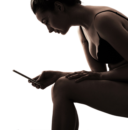 Sensual young woman wearing sexy lingerie and using smartphoneの写真素材