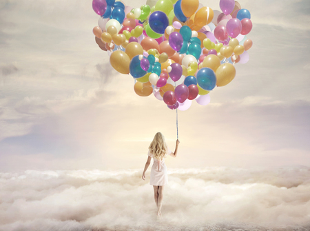 Conceptual picture of a woman holding hundreds of colorful balloonsの写真素材