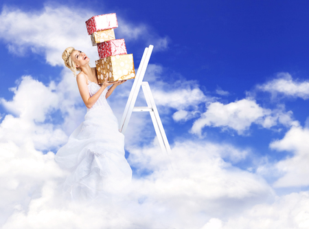 Attractive, blond bride holding a bunch of presents - heaven conceptの写真素材