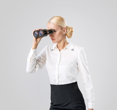 Elegant, blond businesswoman looking through the binocularsの写真素材