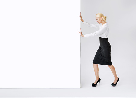 Elegant businesswoman pushing a giant empty commercial boardの写真素材