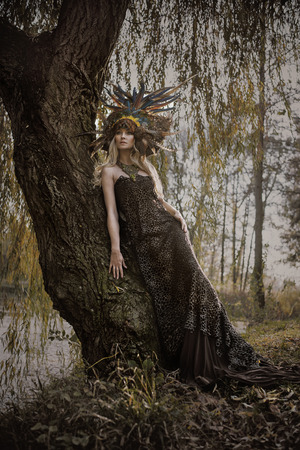 Art portrait of a blond nymph posing in the autumnal parkの写真素材
