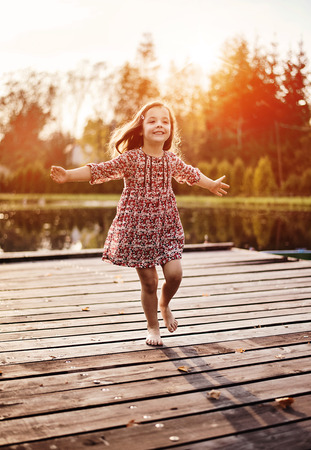 Cheerful and littlel girl realxing on a jettyの写真素材