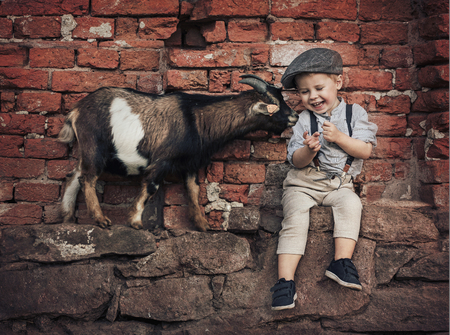 Cute little gentleman with a friendly goatの写真素材